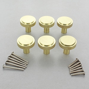 May include: Six gold-toned round cabinet knobs with a textured design and a screw-on base. The knobs are arranged in two rows of three. There are also eight silver screws included.