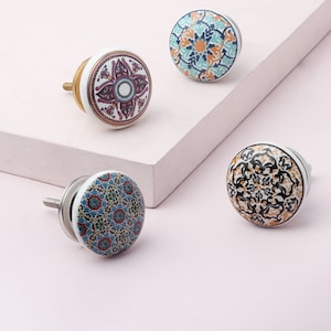 May include: Four ceramic cabinet knobs with intricate floral and geometric patterns in shades of blue, green, orange, red, black, and white.