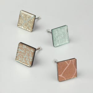 Peut inclure: Quatre boutons de placard carrés de couleurs variées : or, vert, bronze et cuivre. Chaque bouton présente un motif texturé unique et une vis argentée. Ces boutons décoratifs sont parfaits pour moderniser les meubles.