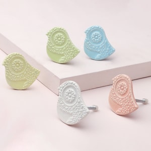May include: Five ceramic bird-shaped drawer pulls in various pastel colours. The pulls have a detailed floral design and come with silver screws.