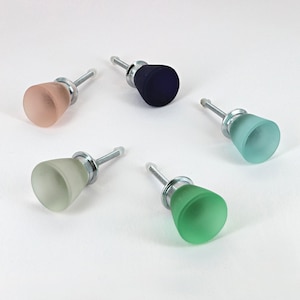 Peut inclure: Cinq boutons de cabinet en verre avec des tiges en métal argenté. Les boutons sont de différentes couleurs : rose clair, vert clair, vert foncé, bleu clair et bleu foncé.