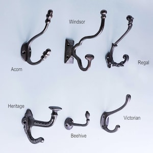 Op de afbeelding: Assortiment van tien gietijzeren haken in verschillende stijlen, waaronder Acorn, Windsor, Regal, Heritage, Beehive en Victorian. De haken zijn allemaal zwart en hebben een rustieke afwerking.