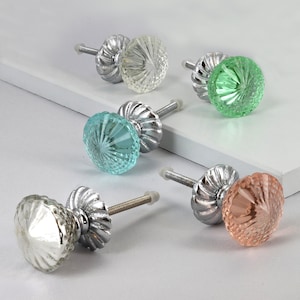 May include: Five decorative cabinet knobs with a silver metal base and a glass top. The glass tops are in various colors, including clear, light blue, green, and pink.