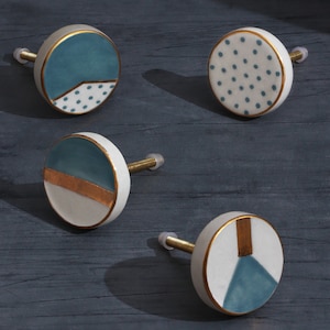 May include: Four ceramic cabinet knobs with gold accents. The knobs feature a blue and white geometric design with polka dots.