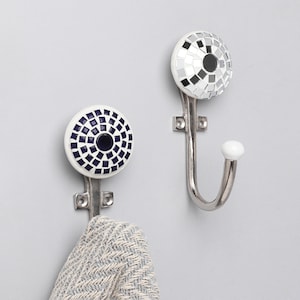 May include: Two silver hooks with white ceramic tops. One hook has a black and white geometric pattern and the other has a blue and white geometric pattern.