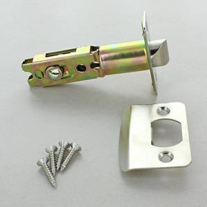 May include: A new door latch set with a silver finish, including the latch mechanism, strike plate, and screws. The latch is made of metal and has a gold and silver finish. The strike plate is rectangular with rounded edges.