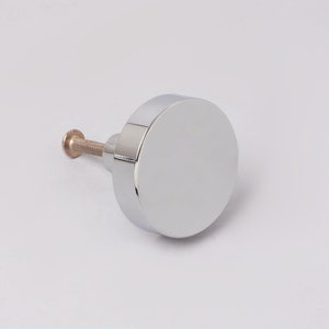 May include: A round, chrome-plated cabinet knob with a screw.