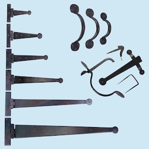 May include: A collection of black wrought iron hardware, including T-hinges of various sizes, curved handles, and latches. The hardware is displayed against a light blue background, highlighting the rustic, handcrafted appearance of the metalwork.