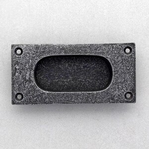 Pode incluir: Uma puxador de armário retangular com aspecto envelhecido, com uma pega oval rebaixada. A ferragem de metal cinza escuro tem uma superfície texturizada e quatro orifícios de montagem, oferecendo uma estética rústica.