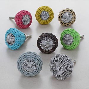 May include: Eight decorative cabinet knobs in a range of colours: pink, yellow, beige, blue, brown, green, grey, and silver. Each knob has a woven texture and a silver metal centre and screw.