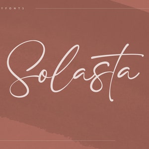 Op de afbeelding: Een wit script lettertype genaamd "Solasta" op een bruine achtergrond. Het lettertype is een cursief script stijl.
