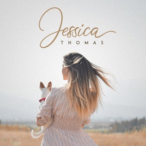 May include: A woman with long blonde hair is holding a small white dog in her arms. She is wearing a striped pink and white dress. The background is a field of dry grass.