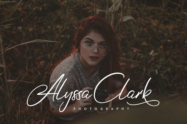 May include: A woman with red hair and glasses is holding a camera in a field of tall grass. The text "Alyssa Clark Photography" is written in a cursive font below her.