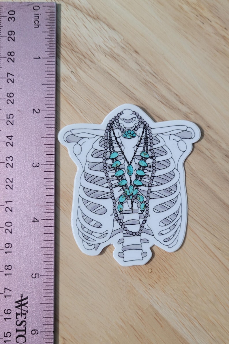 May include: A white sticker with a black outline of a ribcage and a turquoise and silver necklace with turquoise stones. The sticker is approximately 2 inches tall.