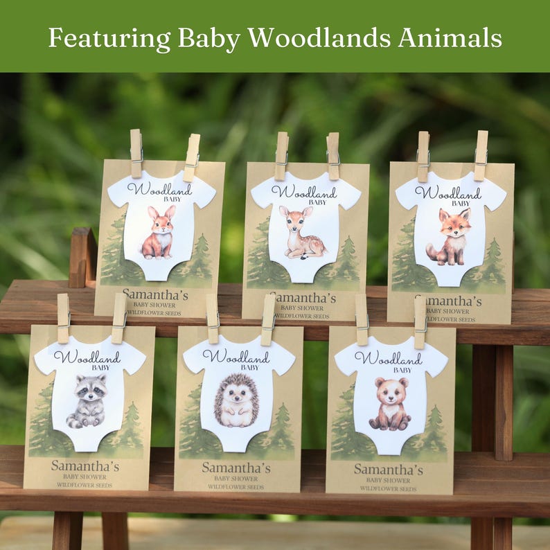 Puede incluir: Seis tarjetas rectangulares con fondos de papel kraft e ilustraciones de bosque verde, cada una con un recorte de body blanco con un animal del bosque en acuarela, sujetas con clips de madera. Texto Woodland Baby, Samantha's Baby Shower Wildflower Seeds.