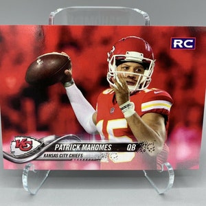 Op de afbeelding: Een rode en witte voetbal trading card met Patrick Mahomes, quarterback voor de Kansas City Chiefs. De kaart heeft een rode achtergrond met een witte rand en de tekst "RC" in de rechterbovenhoek. De kaart heeft ook een zilveren logo voor de Kansas City Chiefs in de linkerbenedenhoek.