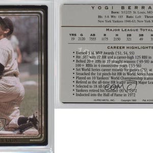May include: A baseball card featuring Yogi Berra, a former New York Yankees catcher. The card is a gold and black design with a photo of Berra in a baseball uniform. The card includes Berra's career statistics and highlights.
