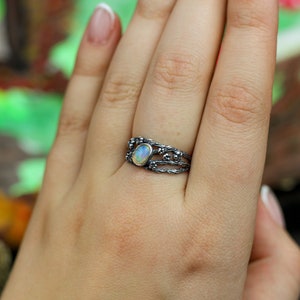 May include: A silver ring with a delicate, intricate design featuring a white opal gemstone.