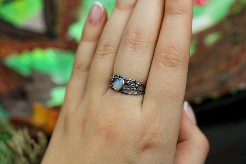 May include: A silver ring with a delicate, intricate design featuring a white opal gemstone.