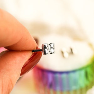 May include: A pair of silver bow-shaped earrings with a textured surface.