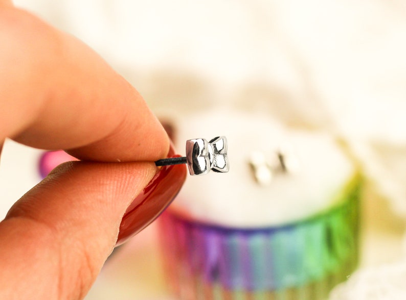 May include: A pair of silver bow-shaped earrings with a textured surface.