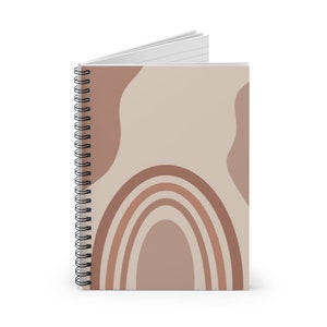 May include: A spiral bound notebook with a beige cover featuring a rainbow design in shades of brown. The cover also has abstract shapes in a lighter brown.