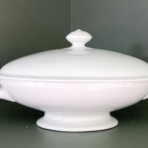 May include: White oval serving dish with a lid and two handles. The dish has a pedestal base.