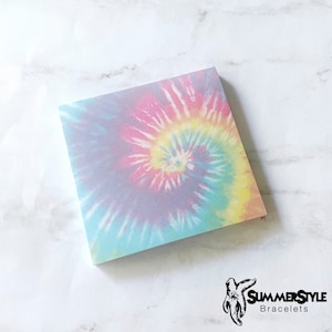 May include: A square sticky note with a tie-dye pattern in shades of blue, pink, yellow, and purple. The pattern is a swirl design.