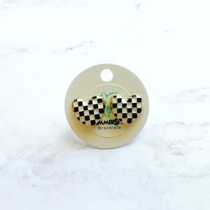 Puede incluir: Un par de pendientes en forma de corazón a cuadros en blanco y negro sobre una tarjeta blanca con el texto "LAMERS Bracelets".