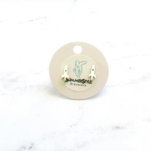 May include: A pair of silver rocket ship stud earrings on a white card with the text "SUMMERSTYLE Bracelets".