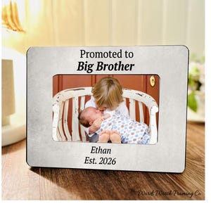 May include: A rectangular photo frame with a distressed silver finish. The frame holds a photo of two children. The text "Promoted to Big Brother", "Ethan", and "Est. 2026" are printed on the frame.