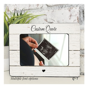 May include: White wooden picture frame with a distressed finish, holding an ultrasound image. The frame has the text "Custom Quote" at the top and a small black heart at the bottom. The words "Multiple font options" are at the bottom.