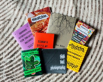 May include: A collection of small, colorful, handmade zines with titles like "Summer Affirmations for the Goth Inclined", "Summer Gives Me", "The Rite", "Bad Bat Photography", "Earthquake Nightmares", "Snack Opinions", and "I Live with a Haunted Plant".