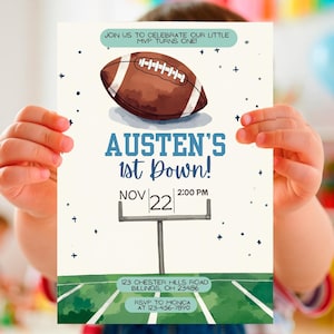 Puede incluir: Una invitación de cumpleaños con temática de fútbol. El diseño incluye una ilustración de un balón de fútbol y el texto "Austen's 1st Down!" con la fecha y la hora. También incluye el texto "¡Únete a nosotros para celebrar que nuestro pequeño MVP cumple un año!"