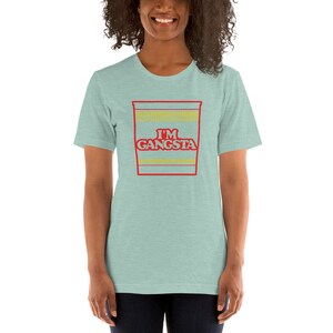 May include: A light blue t-shirt with a red and yellow graphic of a ramen noodle cup with the text "I'M GANGSTA" printed on it.