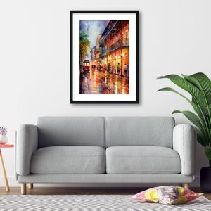 a gray sofa, a framed painting of a city street at night, a small table with a lamp, and a potted plant, all arranged in a living room setting.