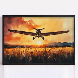 May include: Watercolor painting of a vintage airplane flying low over a wheat field at sunset. The sky is filled with orange and yellow hues, and the plane is silhouetted against the sun. The artwork is framed in a black frame.