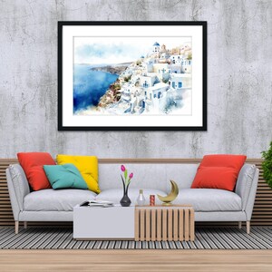 a modern living room with a gray sofa, a coffee table, and a framed painting of a coastal town. The painting is hung on a gray wall above the sofa, which has a wooden frame. The room also includes a potted plant, a lamp, and a vase on the coffee table.