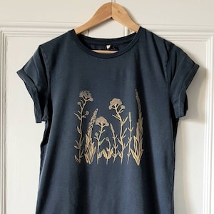 May include: A dark blue t-shirt with a gold floral print. The print features a cluster of stylized flowers and leaves.