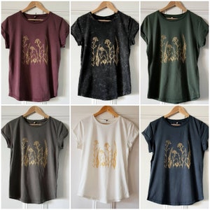 May include: Five t-shirts with a gold floral design on a dark background. The shirts are in burgundy, black, green, gray, and navy blue.