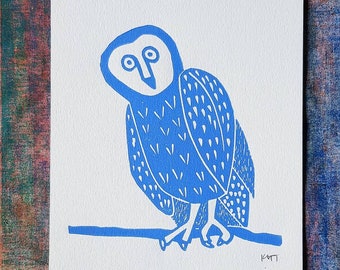 May include: A blue linocut print of an owl perched on a branch. The owl has a white face with large eyes and a small beak. The owl's body is covered in a pattern of small white dots and lines.