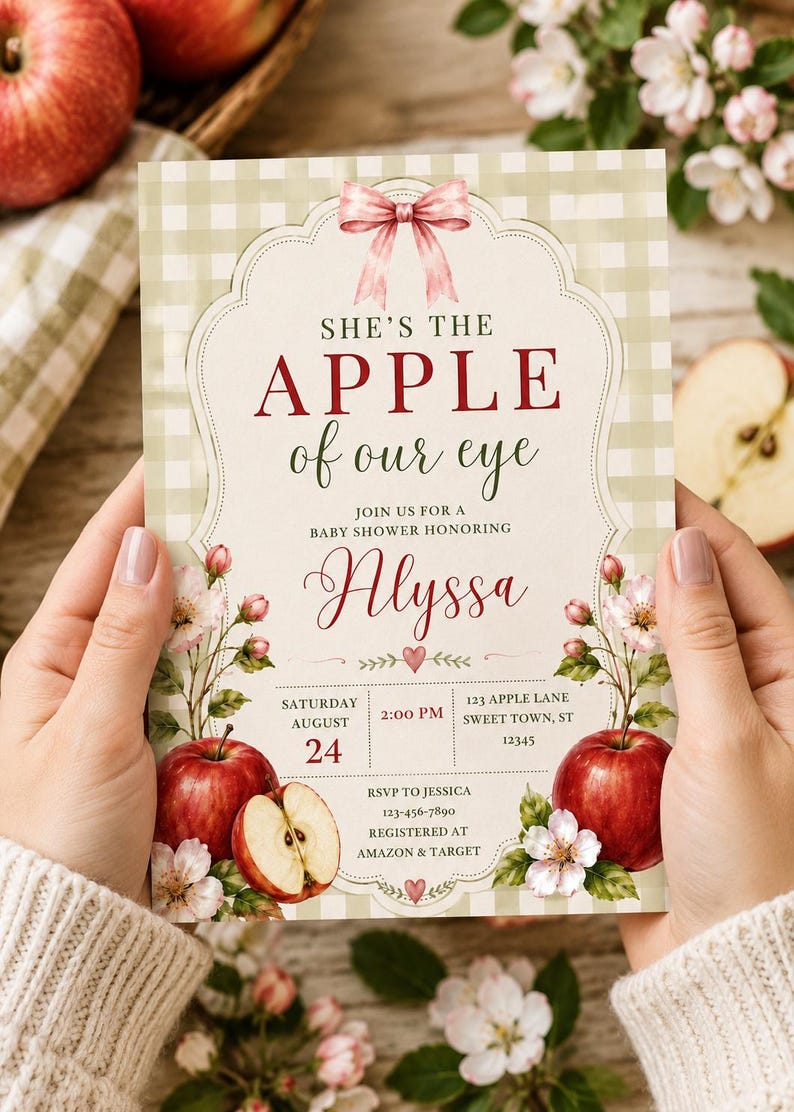 Może przedstawiać: Prostokątne zaproszenie na baby shower z jasnozielonym tłem w kratkę, r&oacute;żową kokardką na g&oacute;rze i ilustracjami czerwonych jabłek. Tekst brzmi: SHE'S THE APPLE of our eye, JOIN US FOR A BABY SHOWER HONORING Alyssa, SATURDAY AUGUST 24, 2:00 PM, 123 APPLE LANE SWEET TOWN, ST 12345, RSVP TO JESSICA 123-456-7890, REGISTERED AT AMAZON & TARGET.