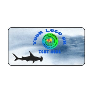 May include: A blue and white watercolor background with a black silhouette of a hammerhead shark. The text "YOUR LOGO OR" is in blue and the text "TEXT HERE" is in green. A circle with the text "YAKKABLES CUSTOM APPAREL AND ACCESSORIES" is in the background.