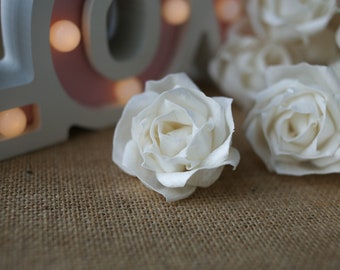 May include: A close-up of white sola wood roses. The roses are arranged on a hessian surface.