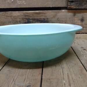 May include: A light blue plastic bowl with a slightly rounded rim. The bowl is sitting on a wooden surface.