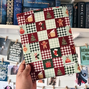 May include: A red and green plaid book sleeve with a Christmas theme. The sleeve features a variety of holiday-themed illustrations, including gingerbread men, candy canes, baubles, and Christmas trees.