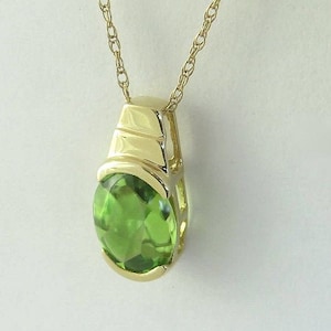 May include: A gold chain necklace with a pendant featuring a green gemstone set in a gold frame.