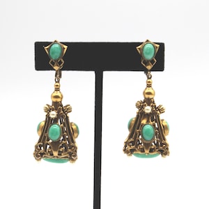 May include: A pair of antique gold-toned earrings with turquoise-colored oval and round stones. The earrings have an ornate, filigree design with a dangling, chandelier-style shape. A small pearl accent is visible.