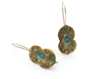 May include: A pair of brass earrings with a floral design. The earrings are a light gold color with a blue-green patina. The earrings are made of two overlapping circles with a raised center.