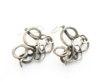 May include: A pair of silver earrings with a unique, organic design. The earrings are made of twisted metal and have a textured finish.